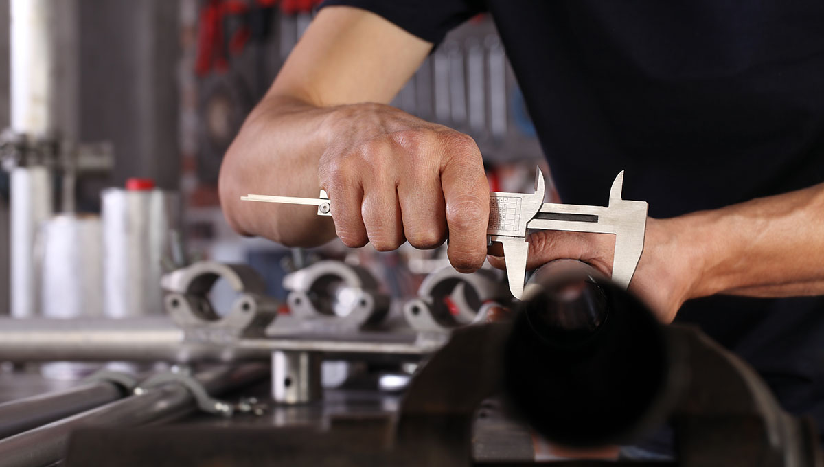 hands man closeup work in home workshop garage with caliper measure metal pipe fixed to the vise on the work bench, diy and craft concept