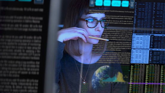 Stock image of a beautiful young woman studying a see through computer screen; contemplating.