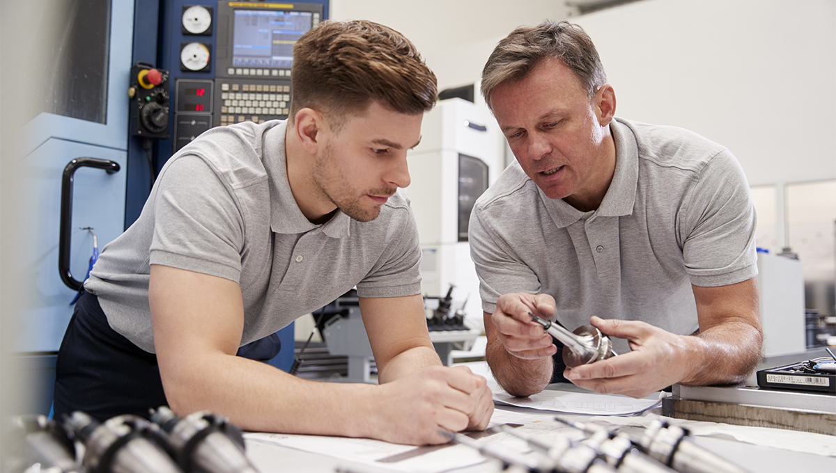 Engineer Showing Apprentice How To Measure CAD Drawings