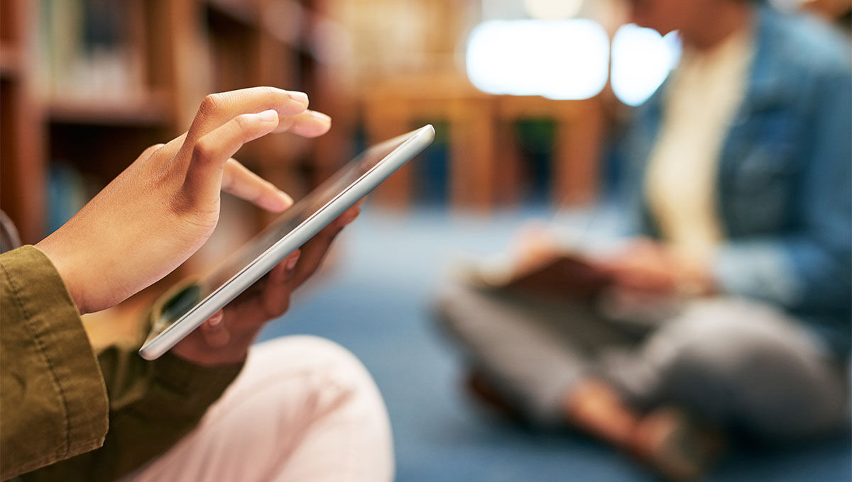 Closeup shot of an unrecognisable university student using a digital tablet in the library at campus