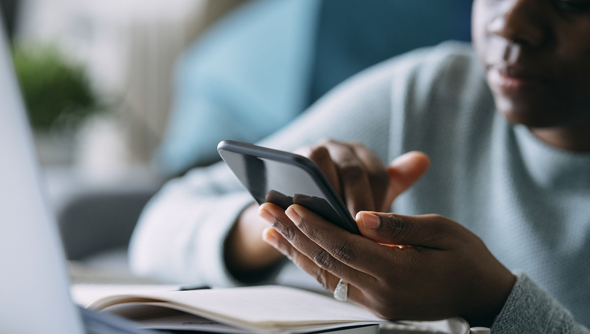 Close up portrait of an anonymous young African American businesswoman using a mobile phone while working remotely from home.