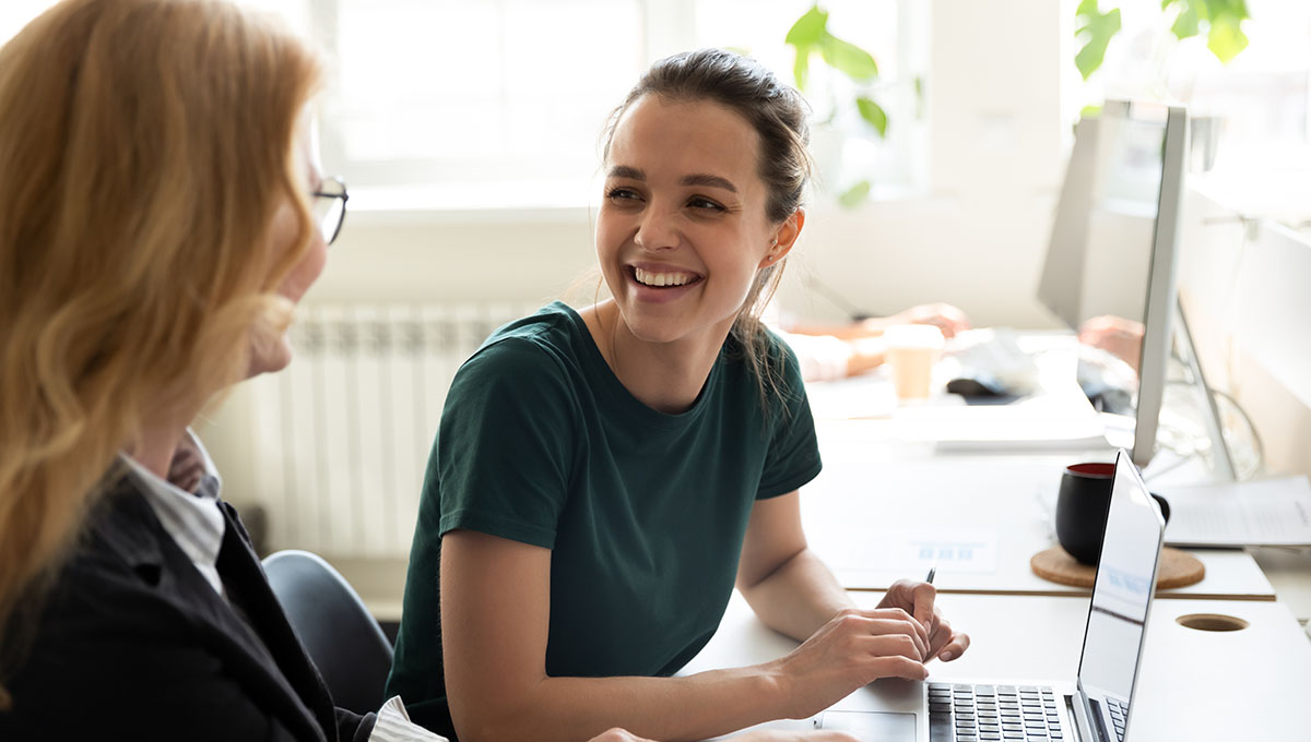 Happy smiling female trainee discussing business ideas with adult trainer