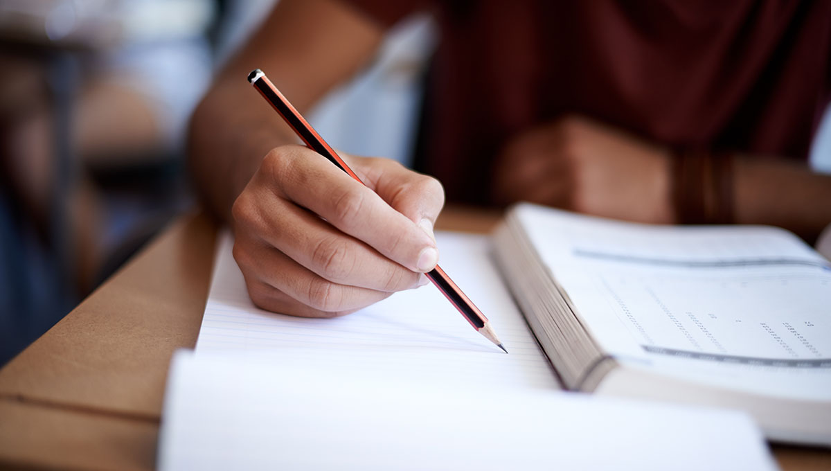 Closeup shot of a young man writing on a note pad