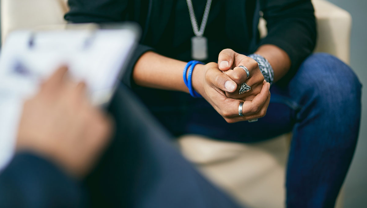 Close-up of African American teenage boy having a session with mental health professional at counselling centre.