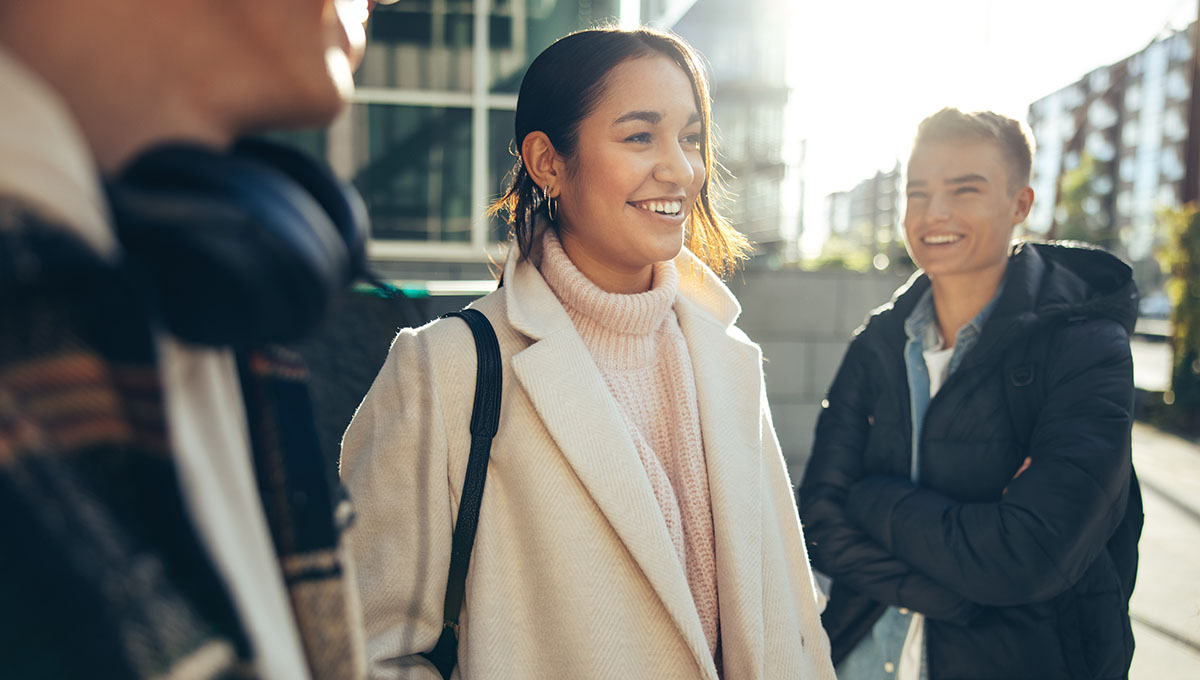 Smiling girl standing in college campus with friends