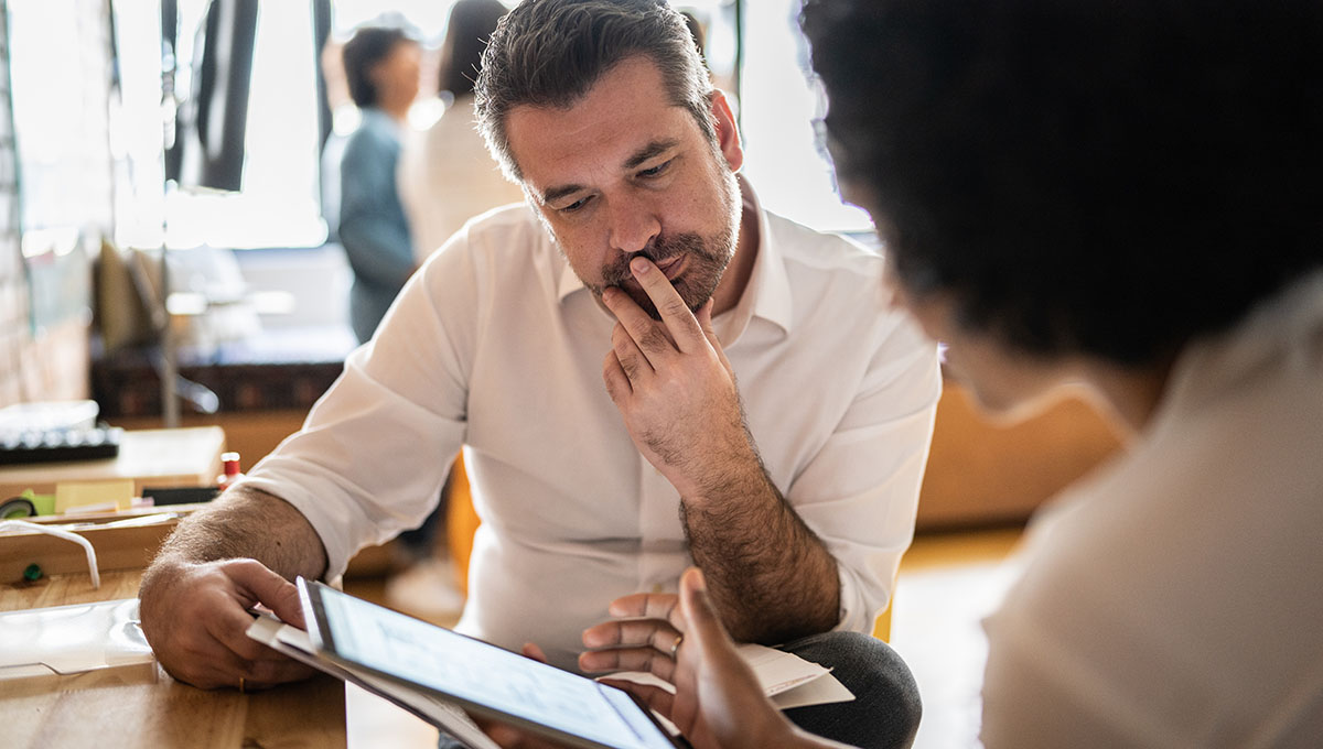 Mature man looking at a digital tablet that a colleague is showing at work