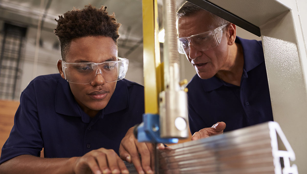 Carpenter Training Male Apprentice To Use Mechanised Saw