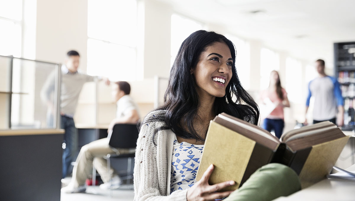 Smiling female student studying in college library